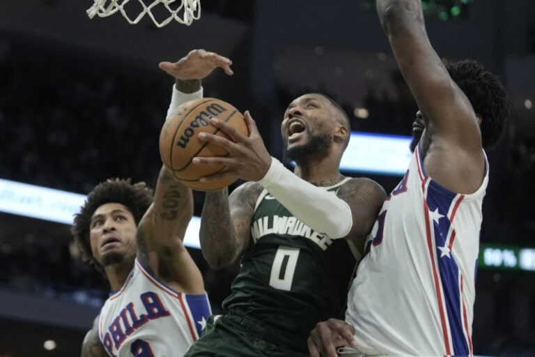 Damian Lillard, de los Bucks de Milwaukee, dispara entre Kelly Oubre Jr. y Joel Embiid, de los 76ers de Filadelfia.AP