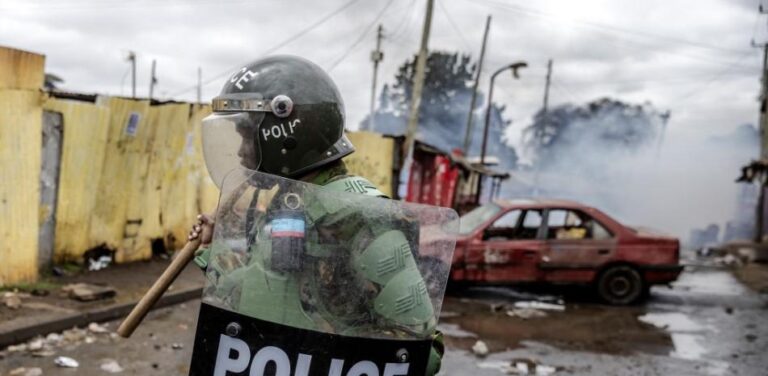 Un oficial de policía de Kenia patrulla junto a un automóvil destrozado que ha sido utilizado como barricada por partidarios de la oposición durante las protestas antigubernamentales en Nairobi el 19 de julio de 2023.AFP
