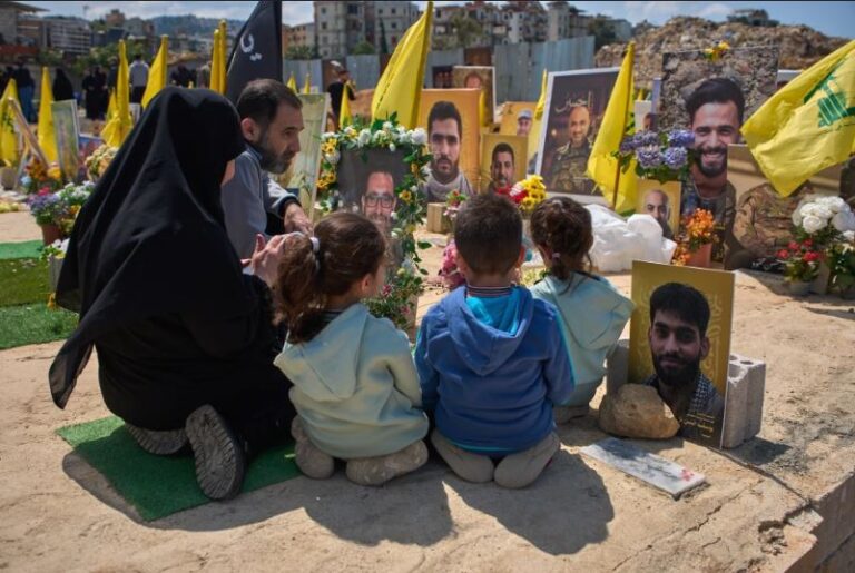 Familiares rezan en la tumba de una persona enterrada junto a combatientes de Hezbollah muertos en ataques israelíes